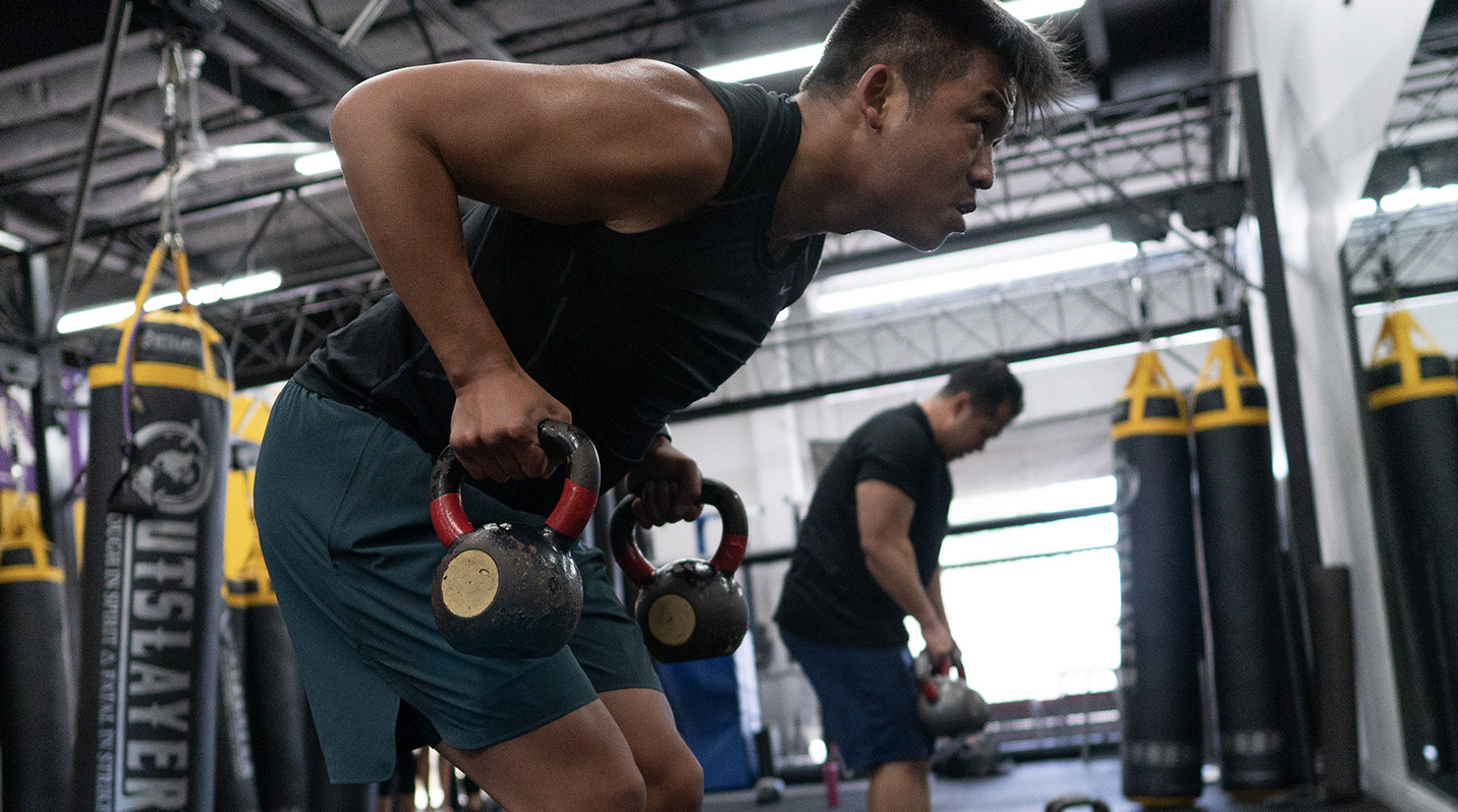 man lifting kettle bells