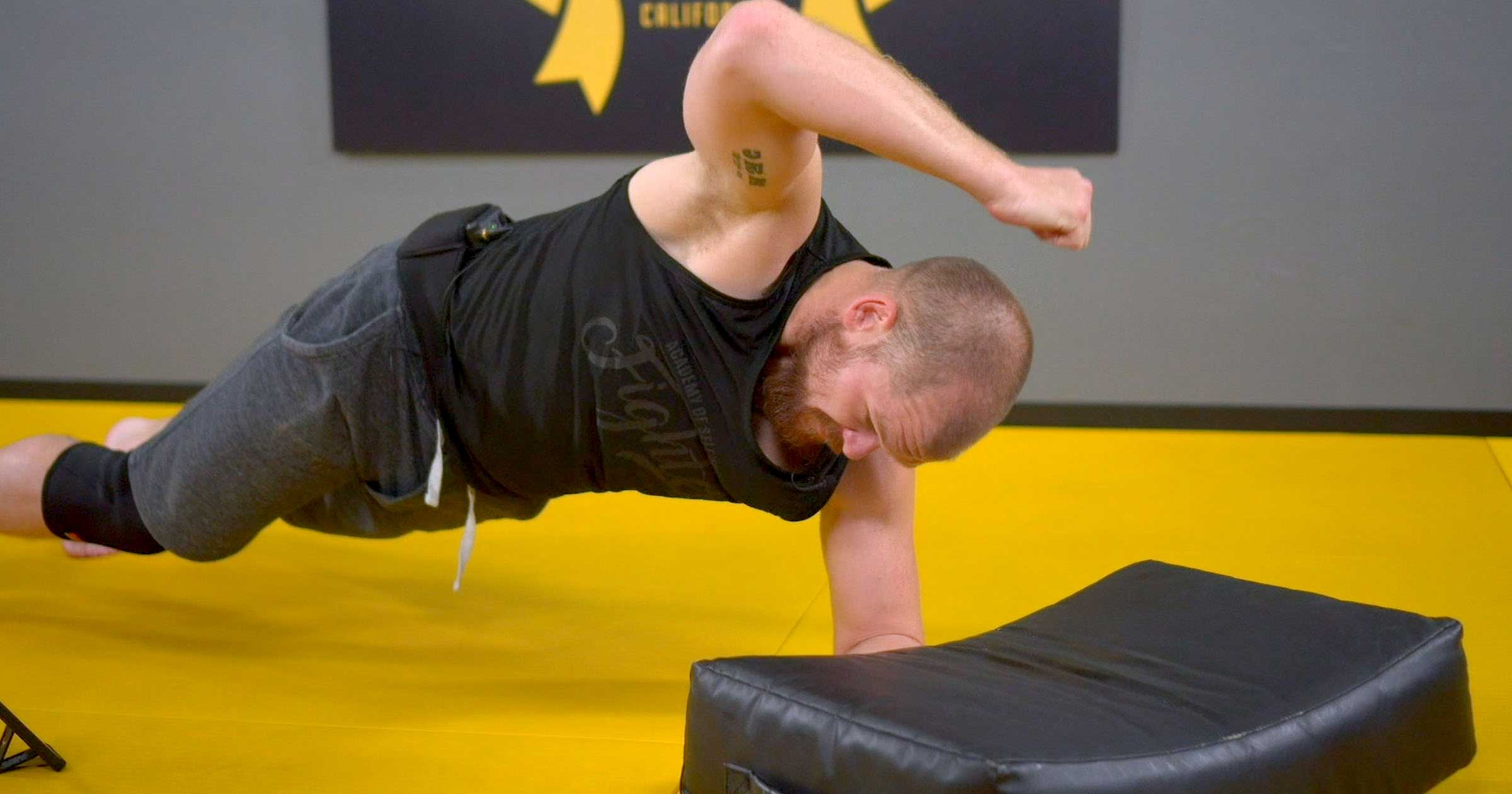 Man doing ground & pound on a pad in plank position.