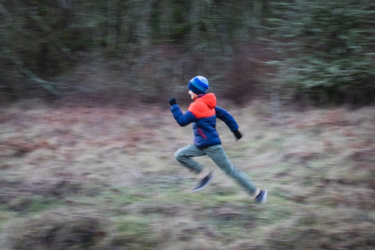 boy running for exercise in forest in winter