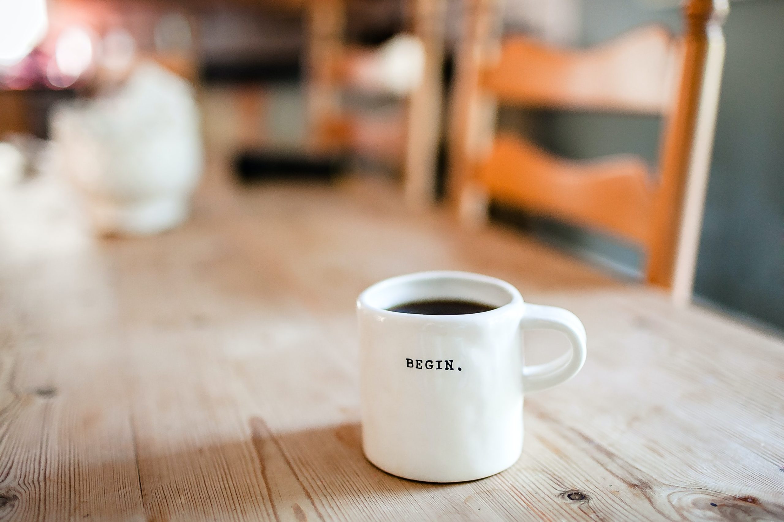lone coffee mug on table inscribed "BEGIN"