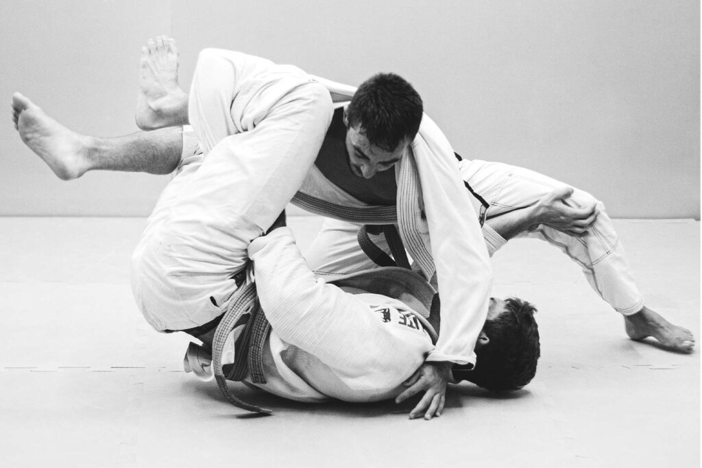 Brazilian Jiu-Jitsu (BJJ), two guys grappling on the mat in white gi's